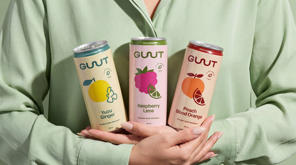 GUUTSy assorted healthy prebiotic soda cans arranged beautifully on a soft pastel background.